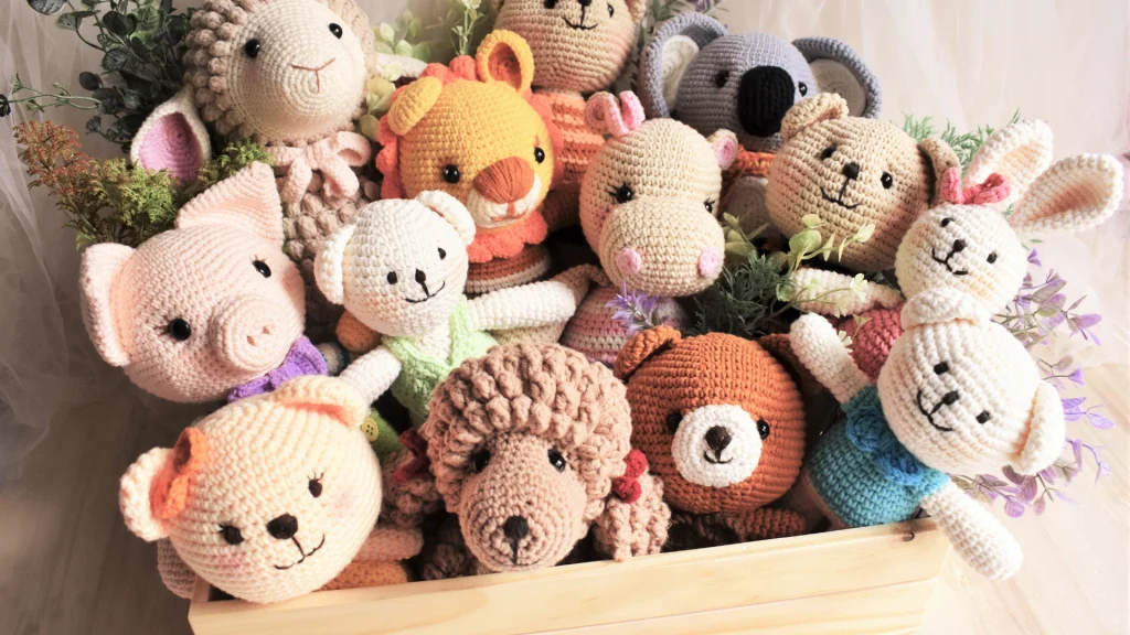 Crochet amigurumi animal toys piled in a wooden crate