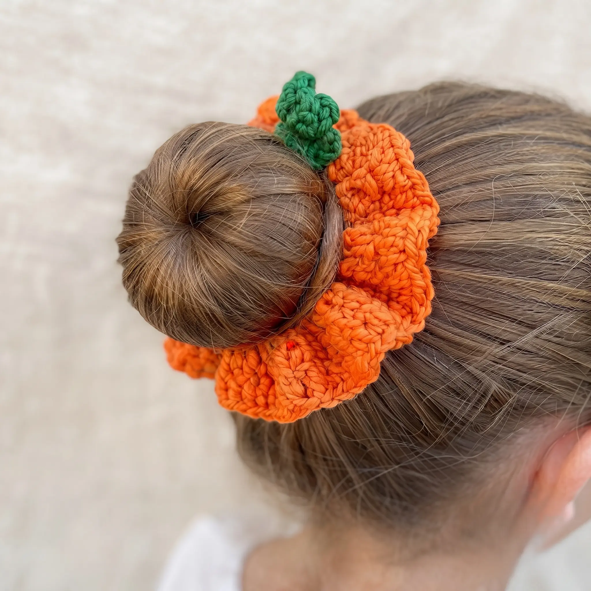 Pumpkin crochet scrunchie worn in hair bun